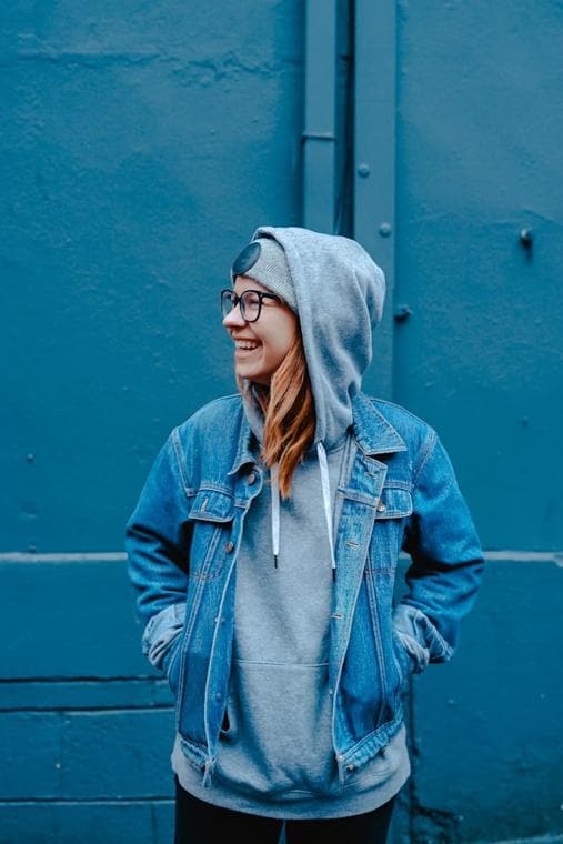 Portrait in a denim jacket against a blue wall