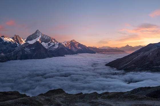 Mountain peaks above a sea of clouds at sunset