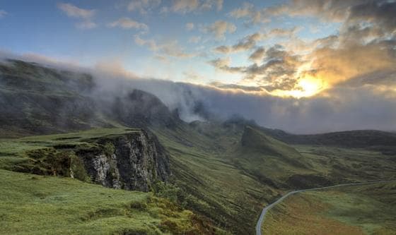 Green hills under low clouds at sunrise